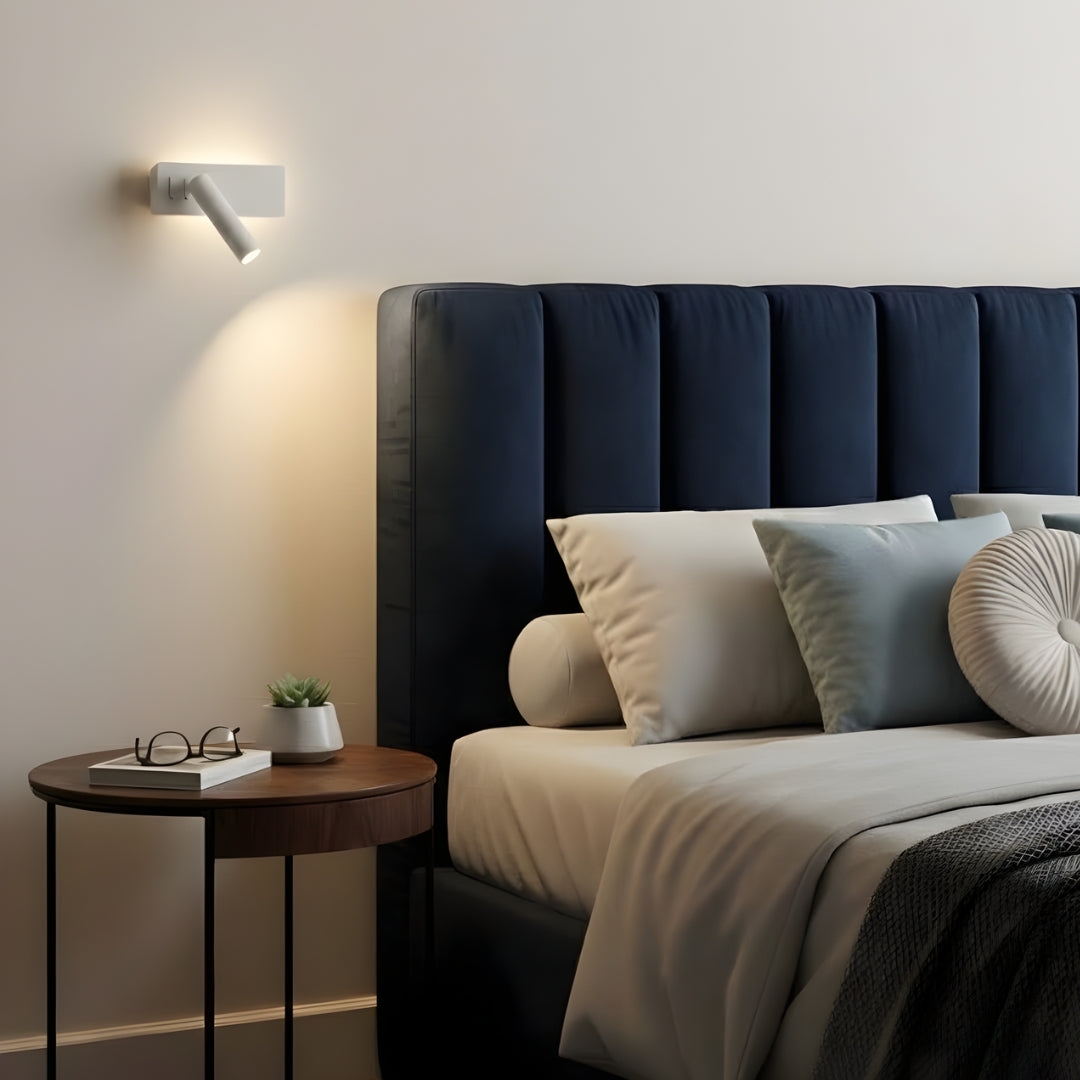 Biała lampa ścienna skierowana na łóżko na białej ścianie.