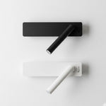 Dwie lampy ścienne, czarna i biała, na białej ścianie.