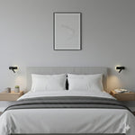 Dwie czarne lampy ścienne po obu stronach dużego łóżka na białej ścianie.